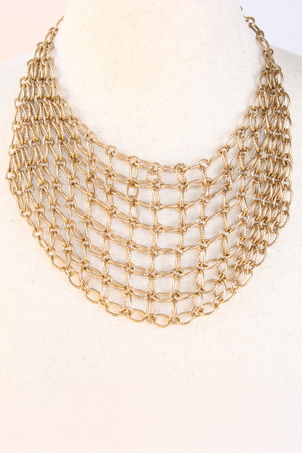 Aqua gold-tone layered chain bib necklace with an open-weave textured link design displayed on a white mannequin bust against a white background.
