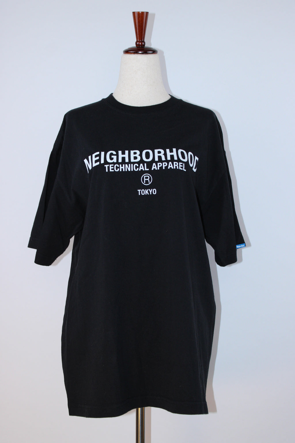 Neighborhood black Technical Apparel Tokyo logo T-shirt with white chest graphic displayed on a mannequin.