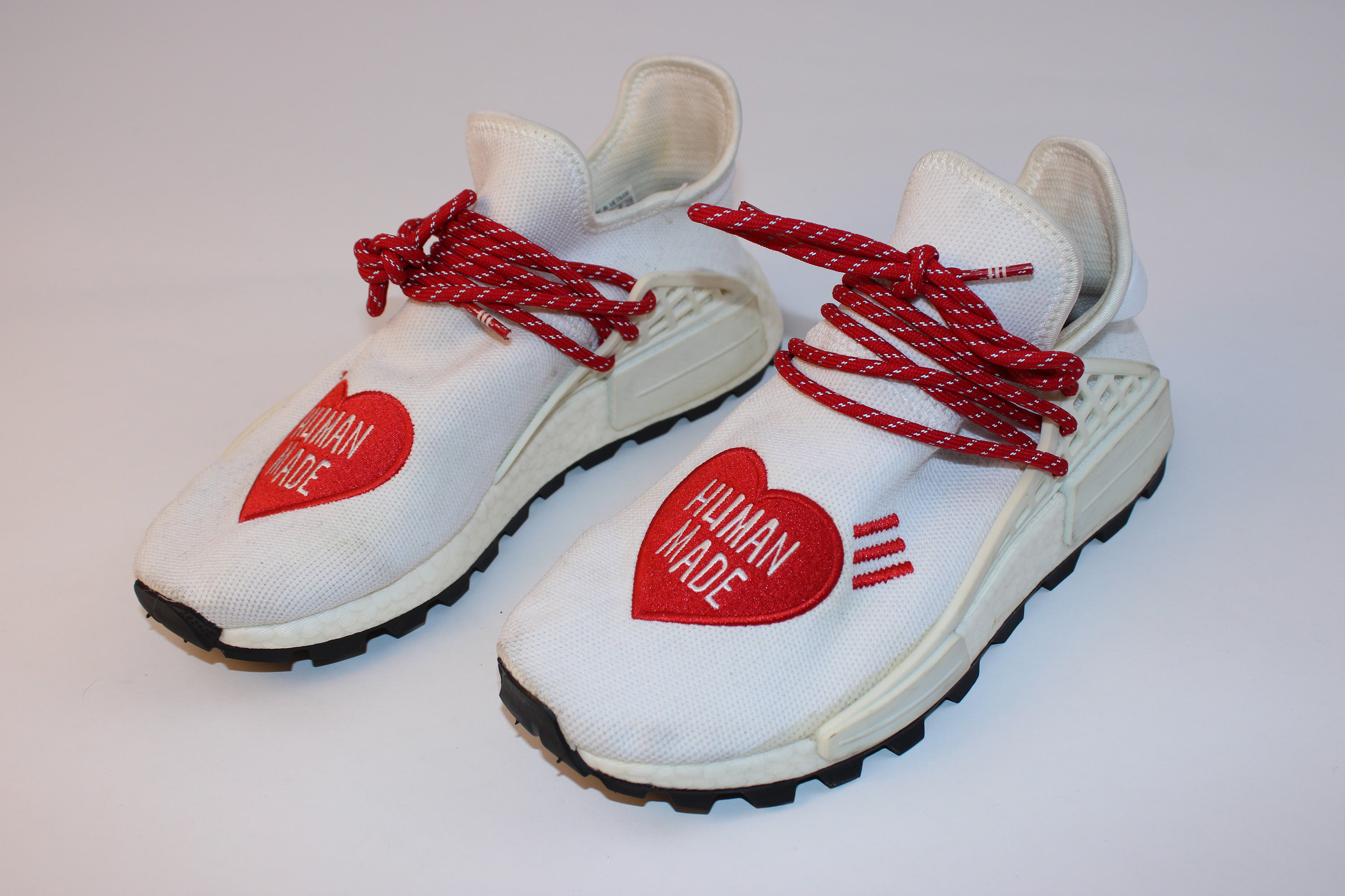 Pharrell Williams Human Made NMD Trail white knit sneakers with red Human Made heart embroidery and Boost sole displayed on a white background.